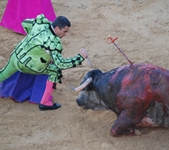 A matador prepares to knife the bull as it lies on the ground bleeding.