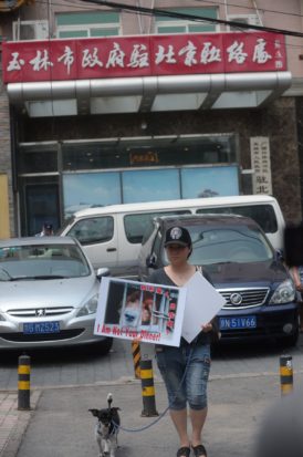 An activist and her dog protest the dog meat festival outside a government office in Yulin.